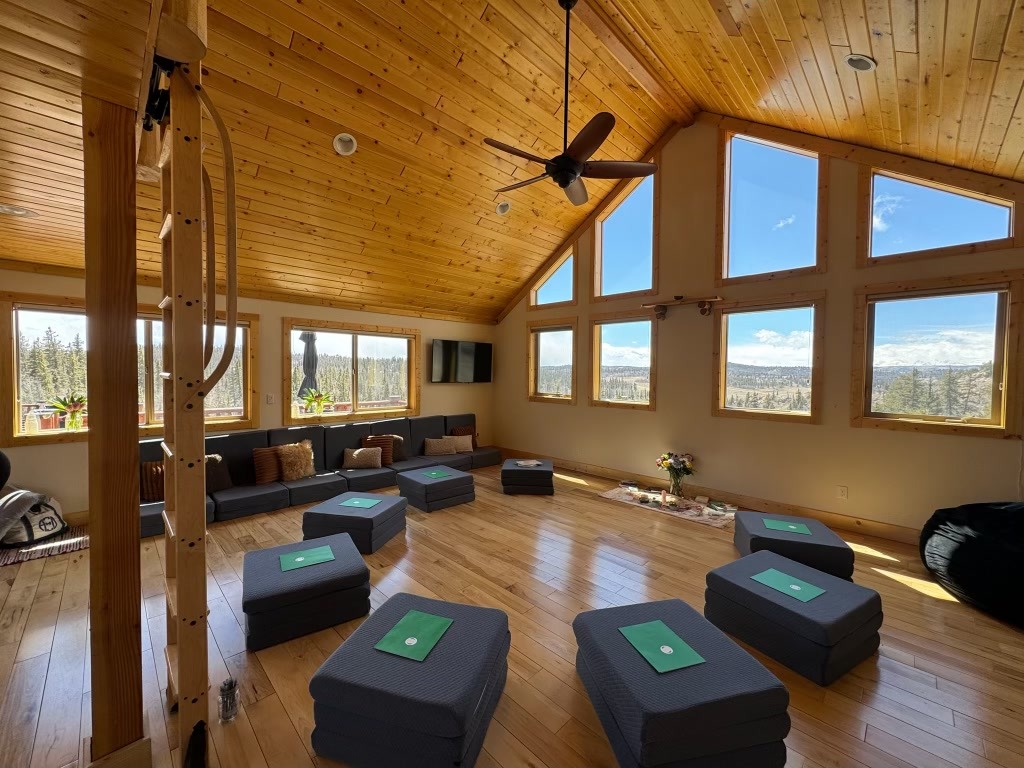 Sunlit vaulted retreat room with meditation cushions and wide mountain windows