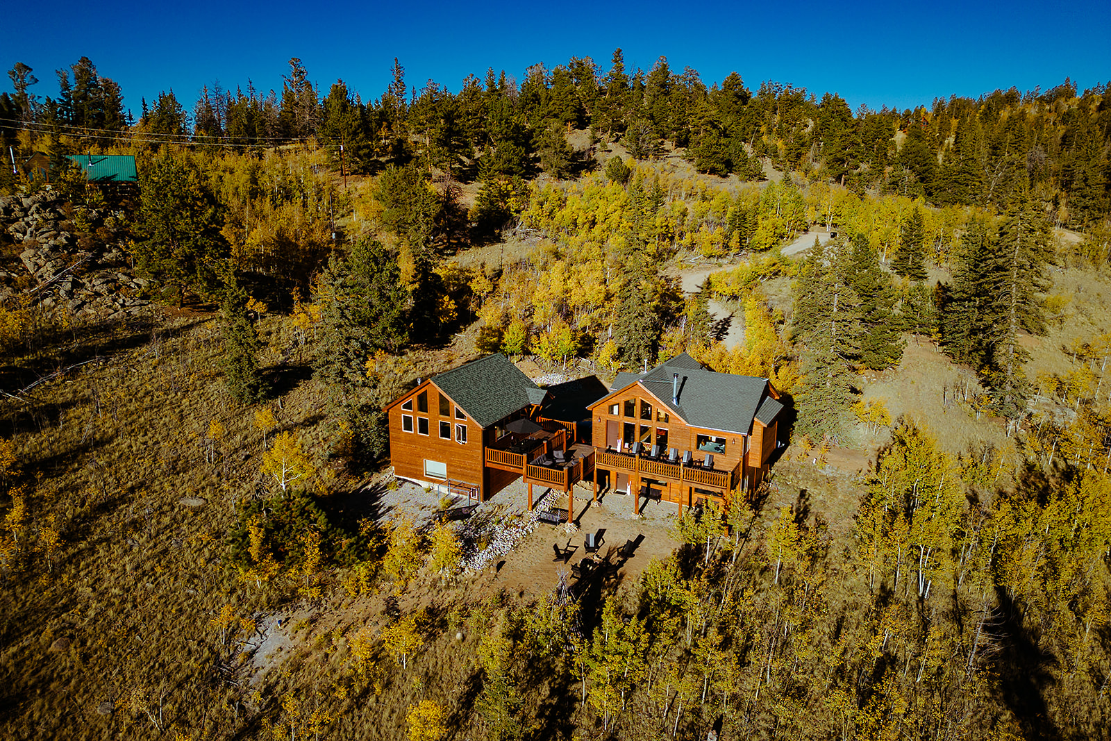 Aerial view of the Freebird Valley retreat cabins surrounded by golden aspens and evergreens in the Rocky Mountains